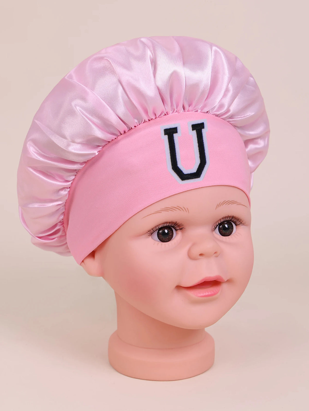 Pink satin sleep cap with a U letter design for a baby