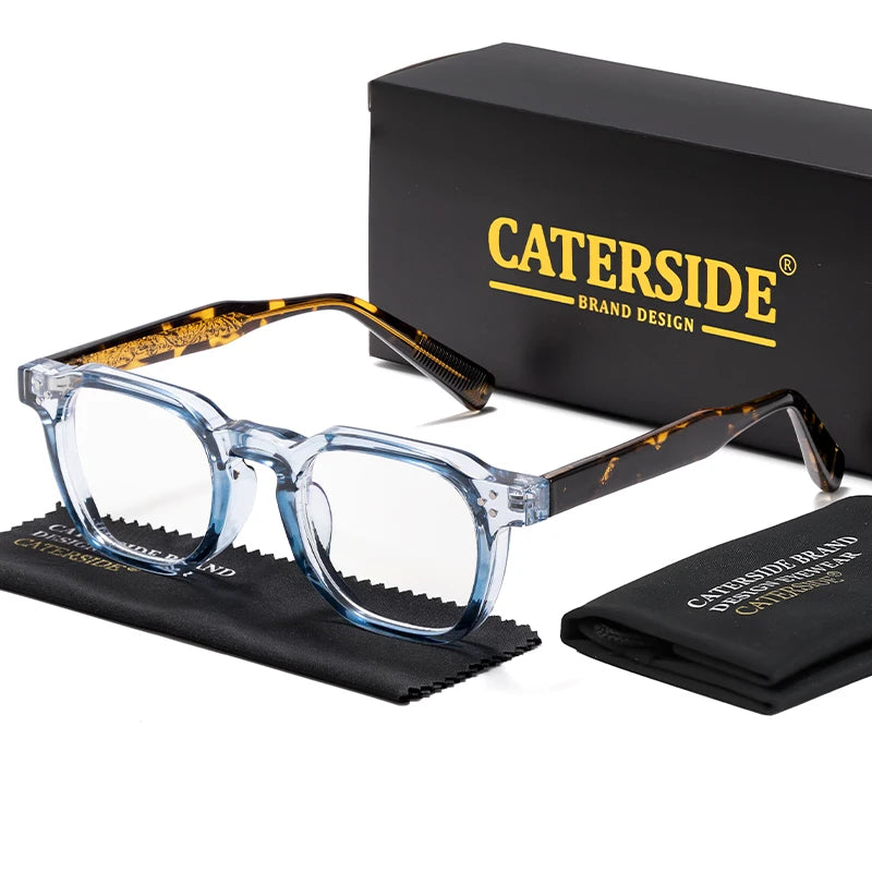 A pair of clear acetate retro square eyeglasses with tortoiseshell accents displayed next to a black box and a folded cloth.