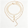 A delicate gold layered necklace featuring pearls and a cross pendant.