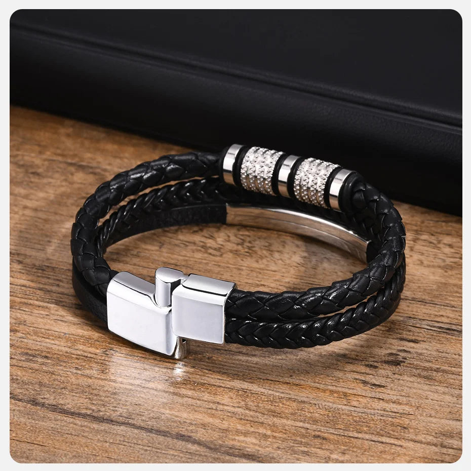 Schwarzes geflochtenes Lederarmband mit silbernen Akzenten auf einer Holzoberfläche