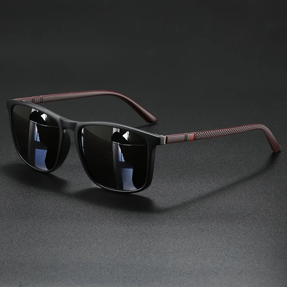 A pair of vintage square polarized cycling sunglasses with dark lenses and a reddish-brown frame resting on a dark surface.
