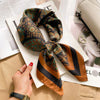 A close-up of a luxurious silk scarf featuring an intricate paisley pattern in shades of teal, gold, and brown, being held by