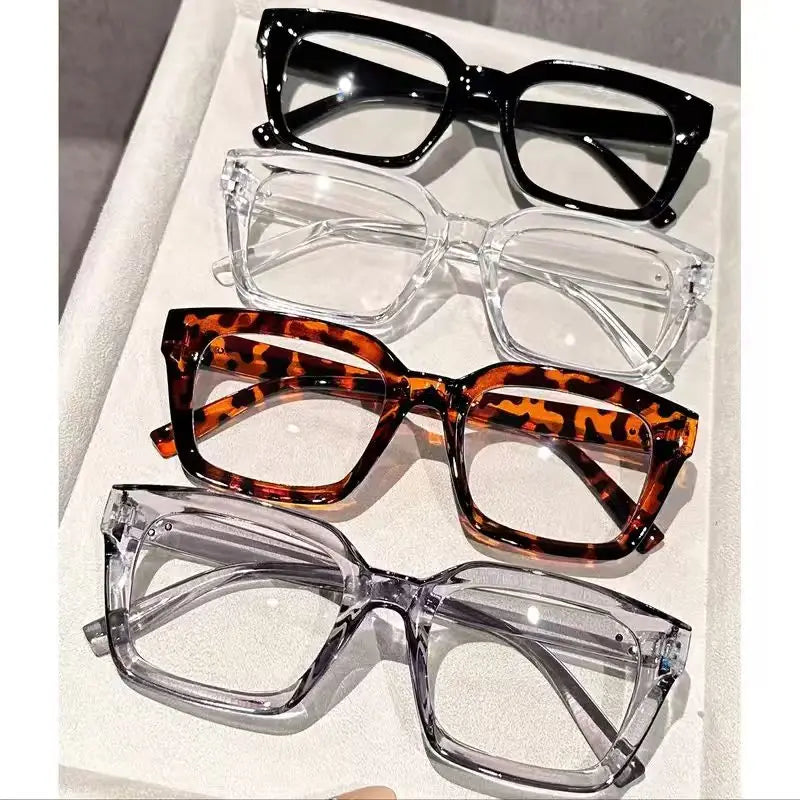 A display of five pairs of classic square reading glasses in black, clear, and leopard print frames.