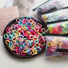 A collection of colorful elastic hair bands in various colors and patterns are displayed on a dark plate with packaged sets.