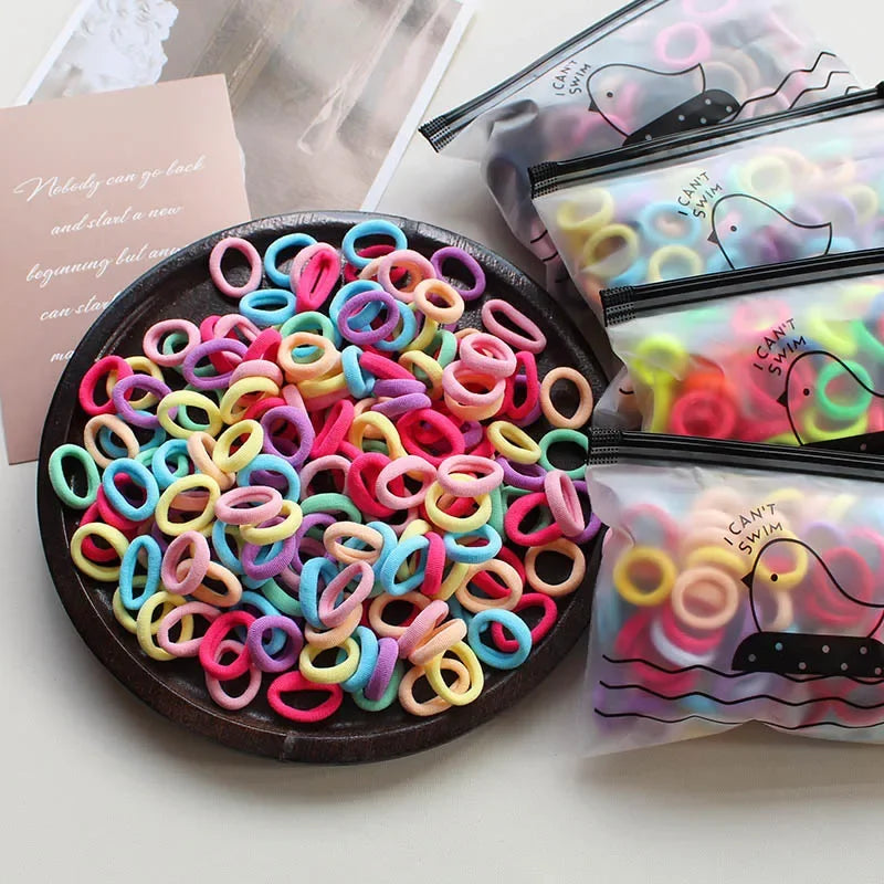 A collection of colorful elastic hair bands in various colors and patterns are displayed on a dark plate with packaged sets.