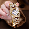 A hand holds a luxury diamond inlaid quartz wristwatch with a gold casing and diamond accents.