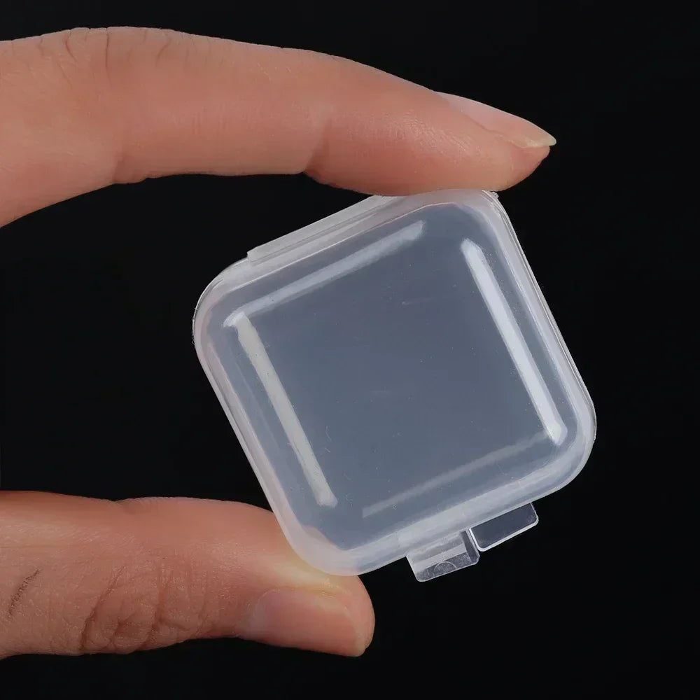 Eine Hand hält eine transparente Mini-Quadrat-Aufbewahrungsbox für Schmuck und Ohrringe vor einem dunklen Hintergrund.