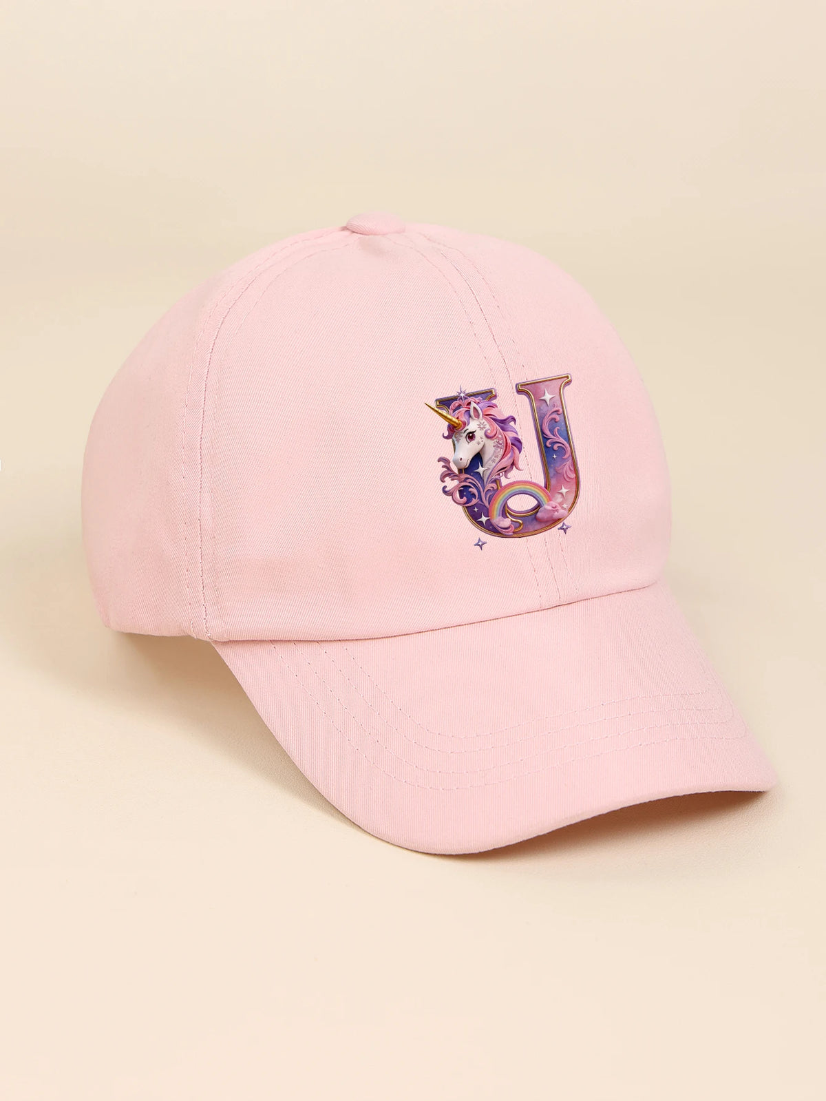A pink baseball cap featuring a purple unicorn letter J embroidered on the front.