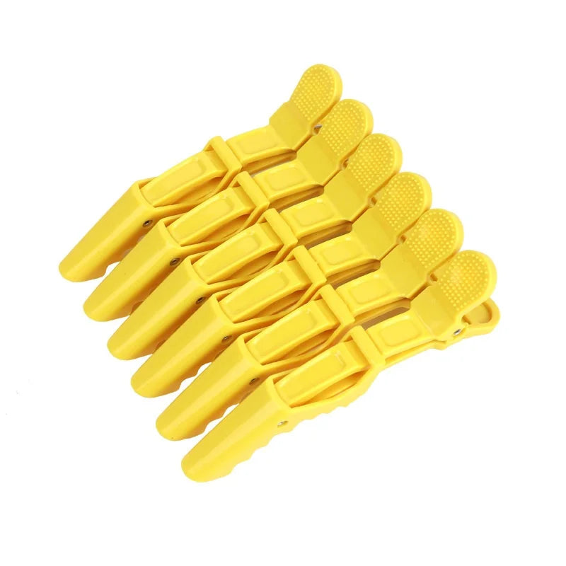 A set of six yellow alligator hair sectioning clips arranged in a row.