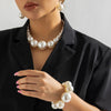 Une femme portant un collier ras-du-cou imitation perles élégant et des boucles d'oreilles assorties, avec une chemise noire 