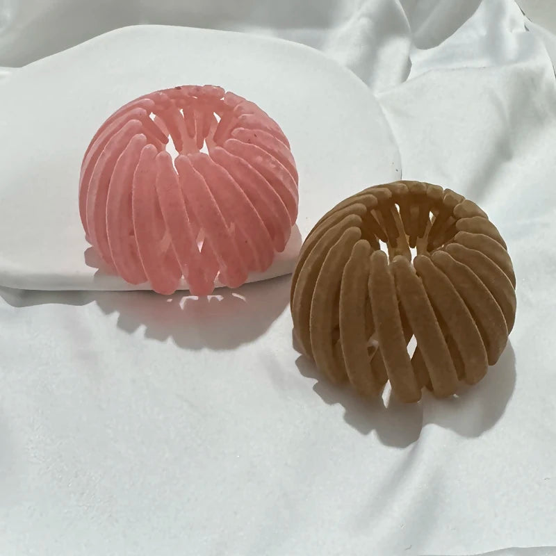 Two round, textured hair clips in pink and brown resting on a white plate.