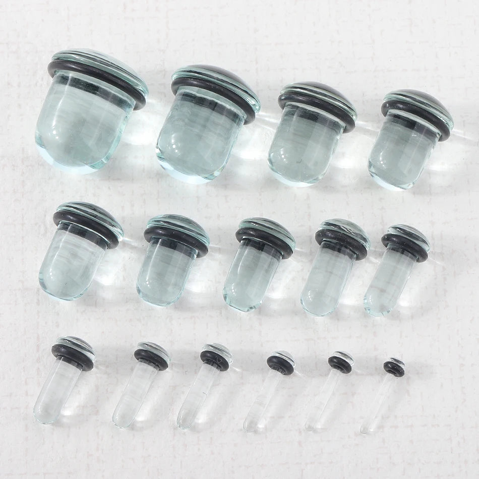 A row of clear glass ear stretching plugs or tunnels arranged horizontally.