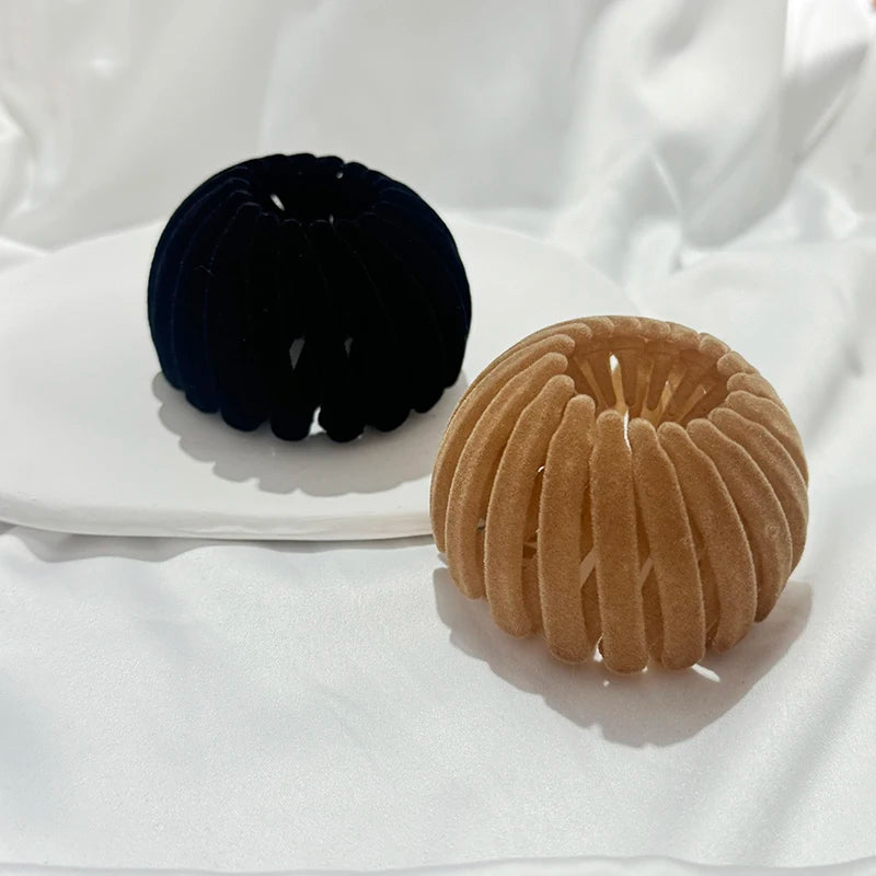 Two elegant horsetail hair clips, one dark navy and one tan, are displayed on a white plate.