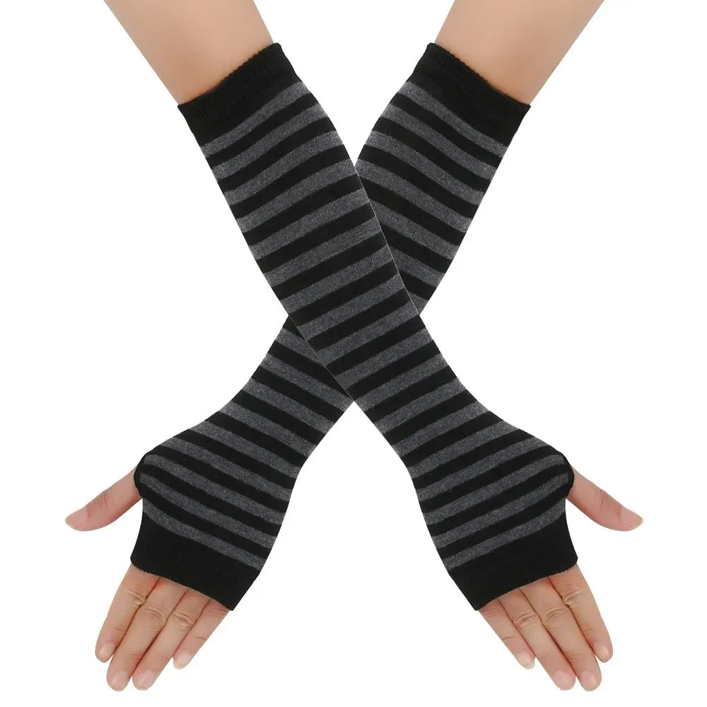 A pair of black and gray striped knitted fingerless gloves crossed on a hand.