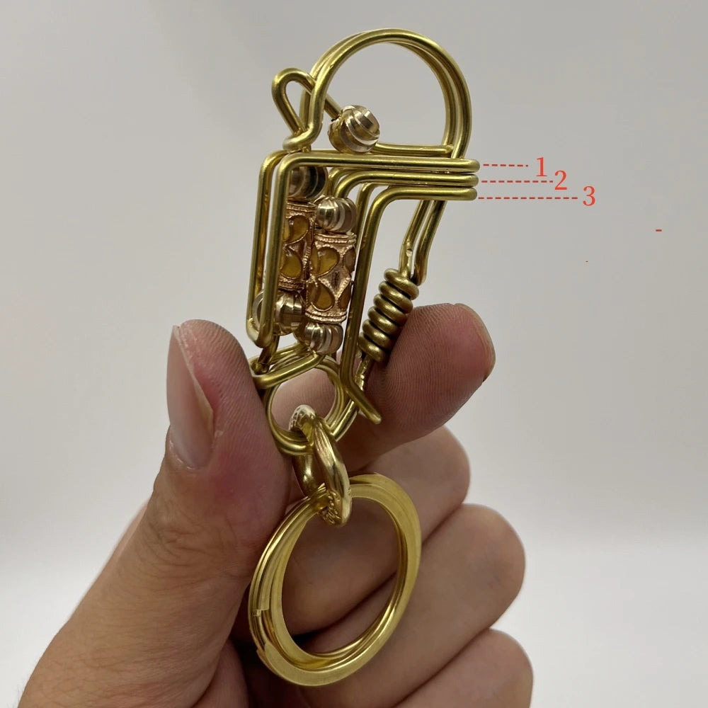 Gros plan d'une clé mécanique en acier inoxydable doré avec un crochet et un anneau, tenue par une main.