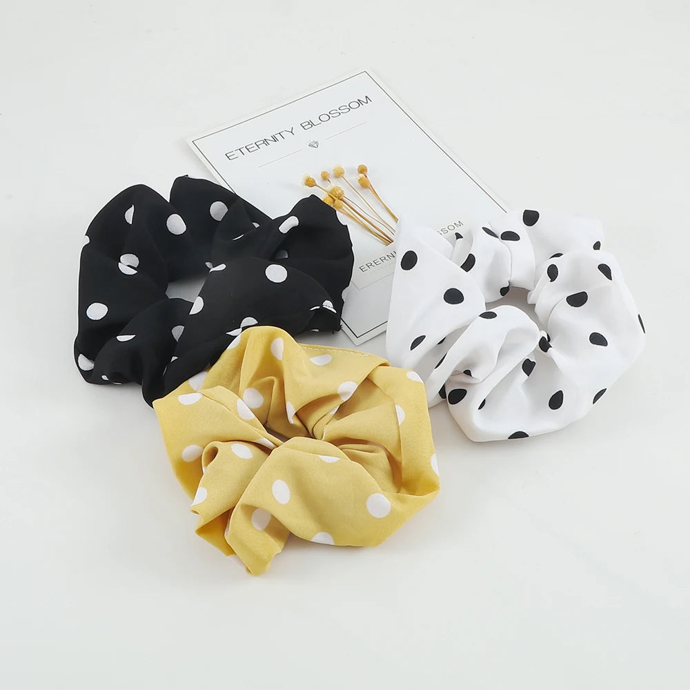 A set of three knitted hair scrunchie headbands featuring black polka dots, white polka dots, and yellow polka dots.