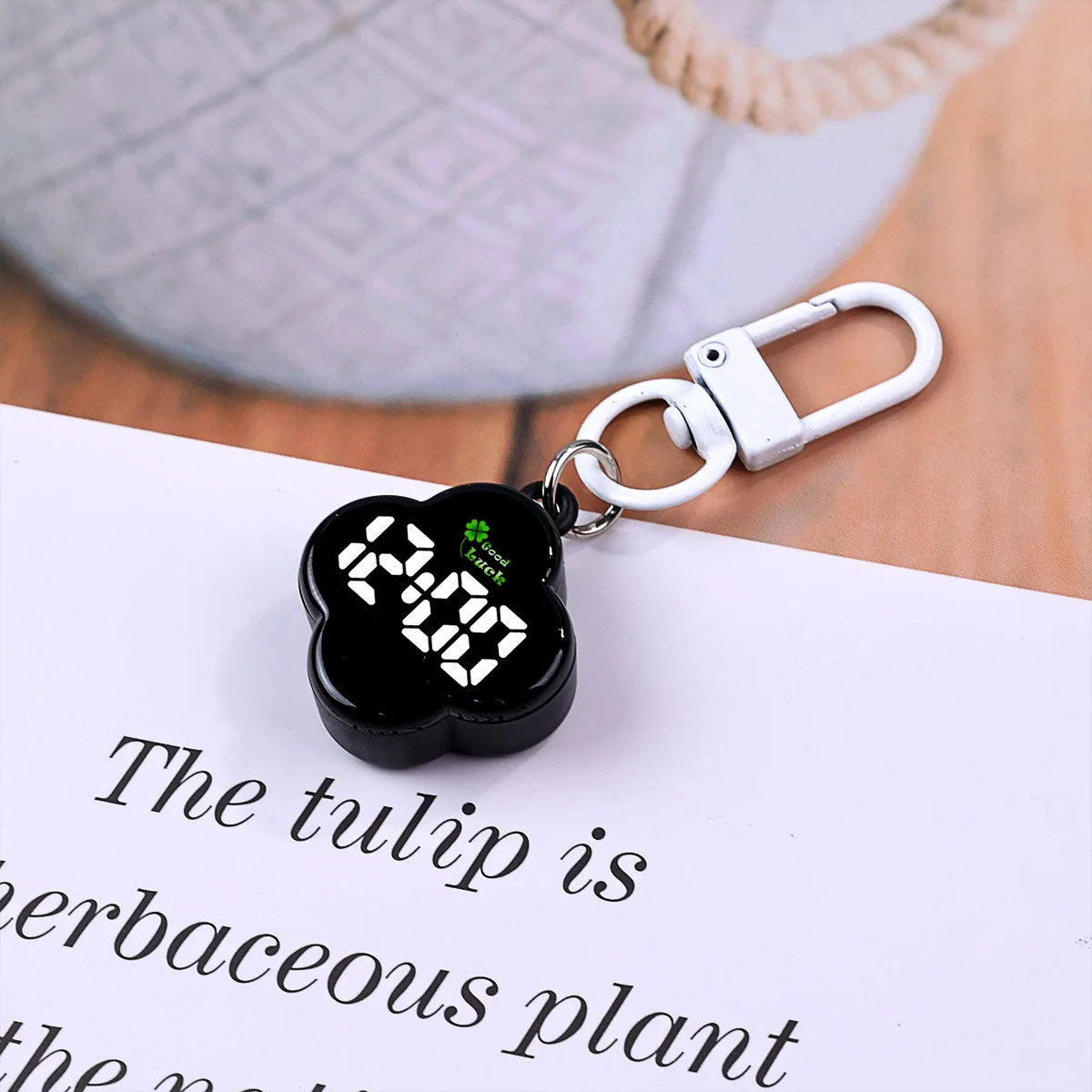 A black LED digital keychain watch with a flower design attached to a silver keyring on a white background.
