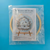 A clear plastic bag containing an embroidery DIY art kit featuring a depiction of a Christmas scene.