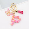 Gold acrylic letter D keychain with a pink butterfly charm and a magenta tassel