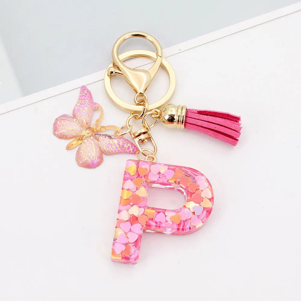 Gold acrylic letter D keychain with a pink butterfly charm and a magenta tassel