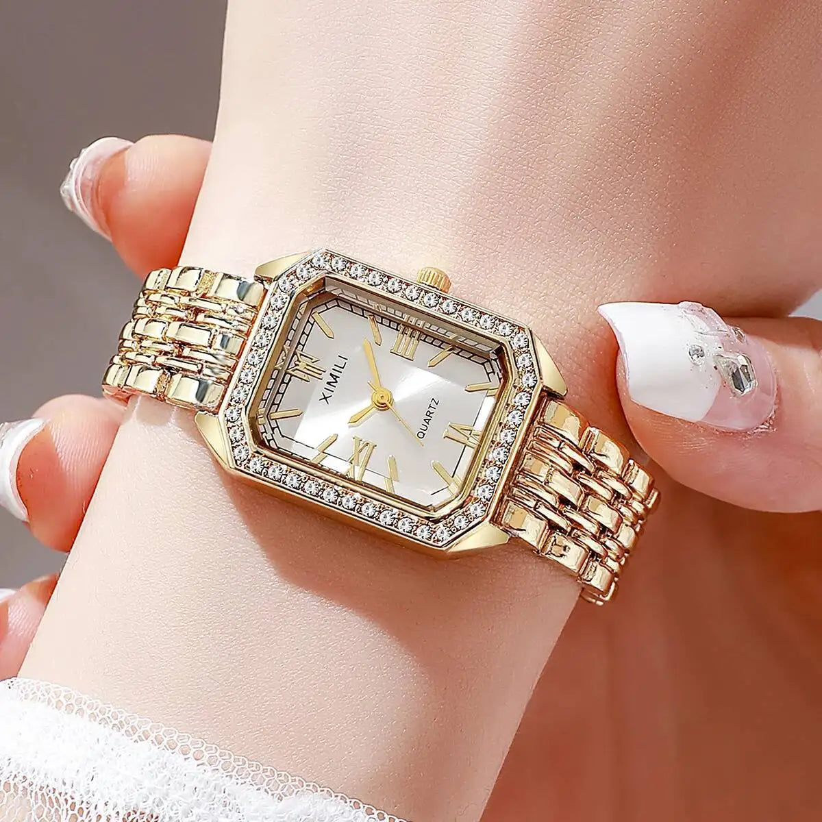 A gold-toned rhinestone quartz wristwatch worn on a woman's wrist.