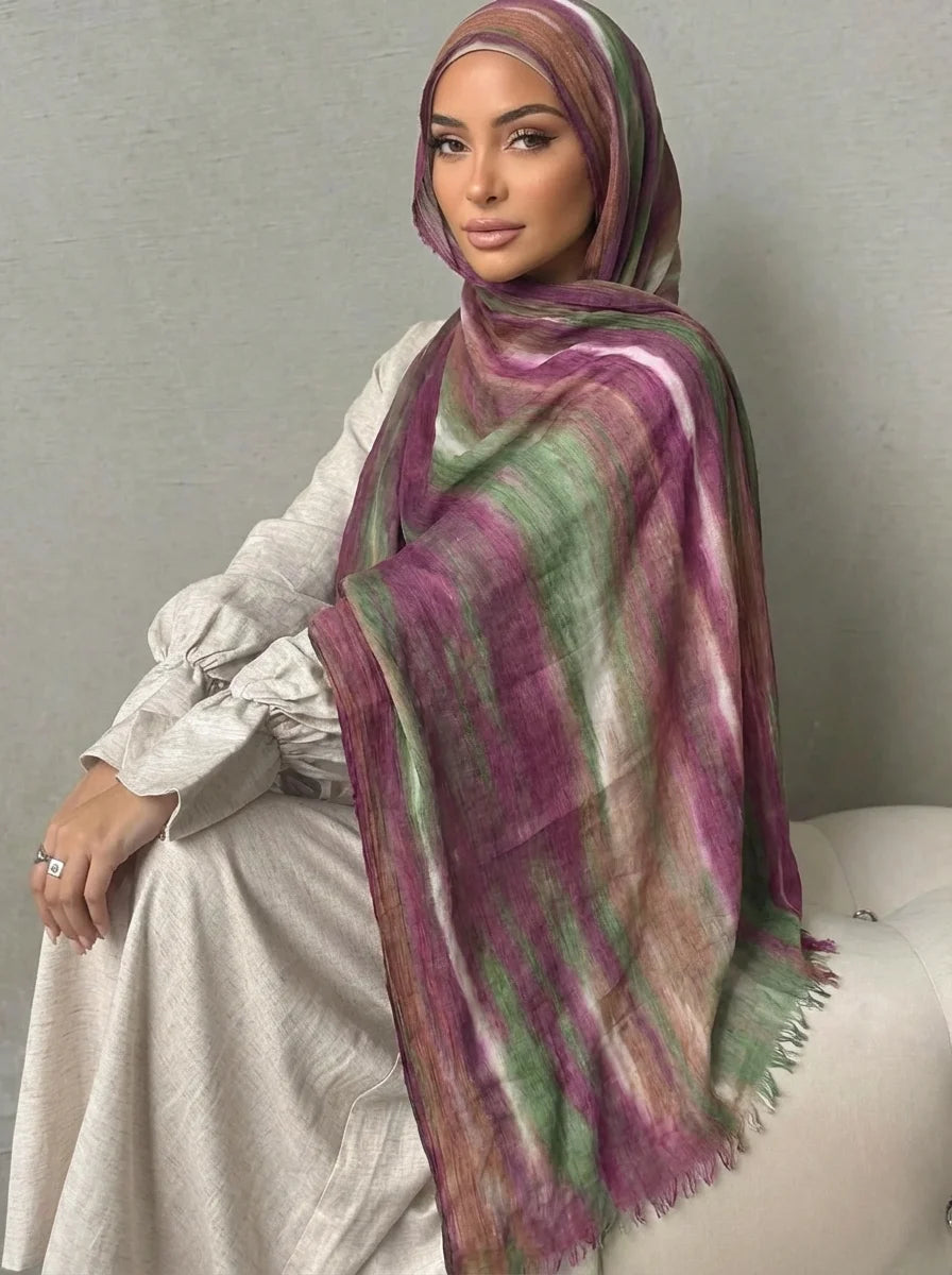 Una mujer vistiendo un elegante pañuelo de hijab de algodón rayón con rayas moradas y verdes.