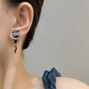 A close-up of a woman's ear showing cute black cat stud earrings.