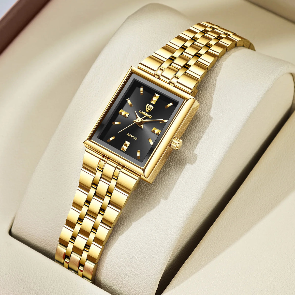 A gold-toned minimalist quartz wristwatch with a black dial and gold accents resting on a beige leather surface.