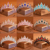 Colección de tiaras y coronas de cristales ornamentadas exhibidas en cajas cuadradas.