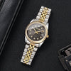 A silver-toned wristwatch with a black dial, gold accents, and a metal bracelet is shown on a dark surface.