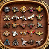 Collection de broches baroques en abeille et insectes détaillées, présentées sur un plateau en bois.