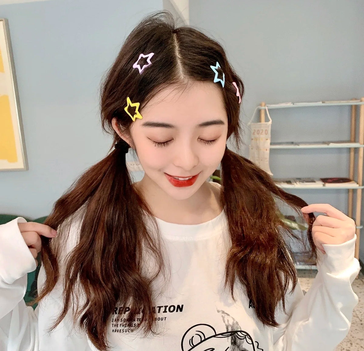 Una mujer joven con cabello castaño largo sostiene unas pinzas para el pelo con forma de estrella y coloridas.