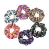 Un set de seis gomas de tela con estampado floral de satén en varios tonos de rosa, púrpura y oro.
