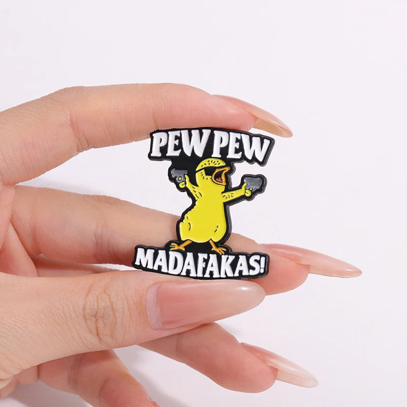 A hand holds a black enamel lapel pin featuring a yellow chicken character and the text PED PEW PEW and MADAFAKAS