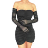 Femme portant une robe noire sans bretelles et de longues gants de danse opéra en filet transparent.