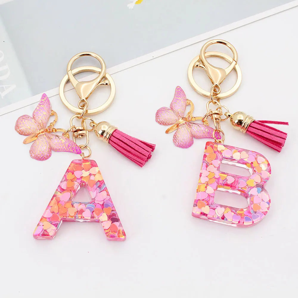 Gold alphabet letter keychain shaped like the letter B with pink butterfly and tassel details