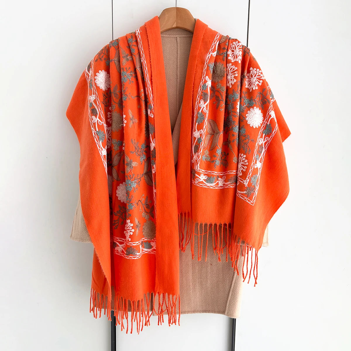 An orange and gray floral scarf with white accents draped on a hanger.