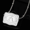 Silver chain necklace with a white initial letter pendant on black fabric.