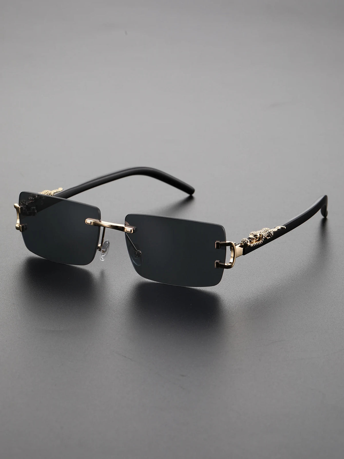 A pair of black rectangular frameless sunglasses resting on a dark gray surface.