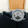 A silver luxury automatic mechanical men's wristwatch with a black leather strap displayed on a dark surface.