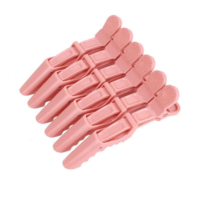 A set of six pink alligator hair sectioning clips arranged in a row.