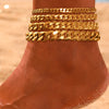 Gold multi-chain stainless steel anklets stacked on a person's foot.