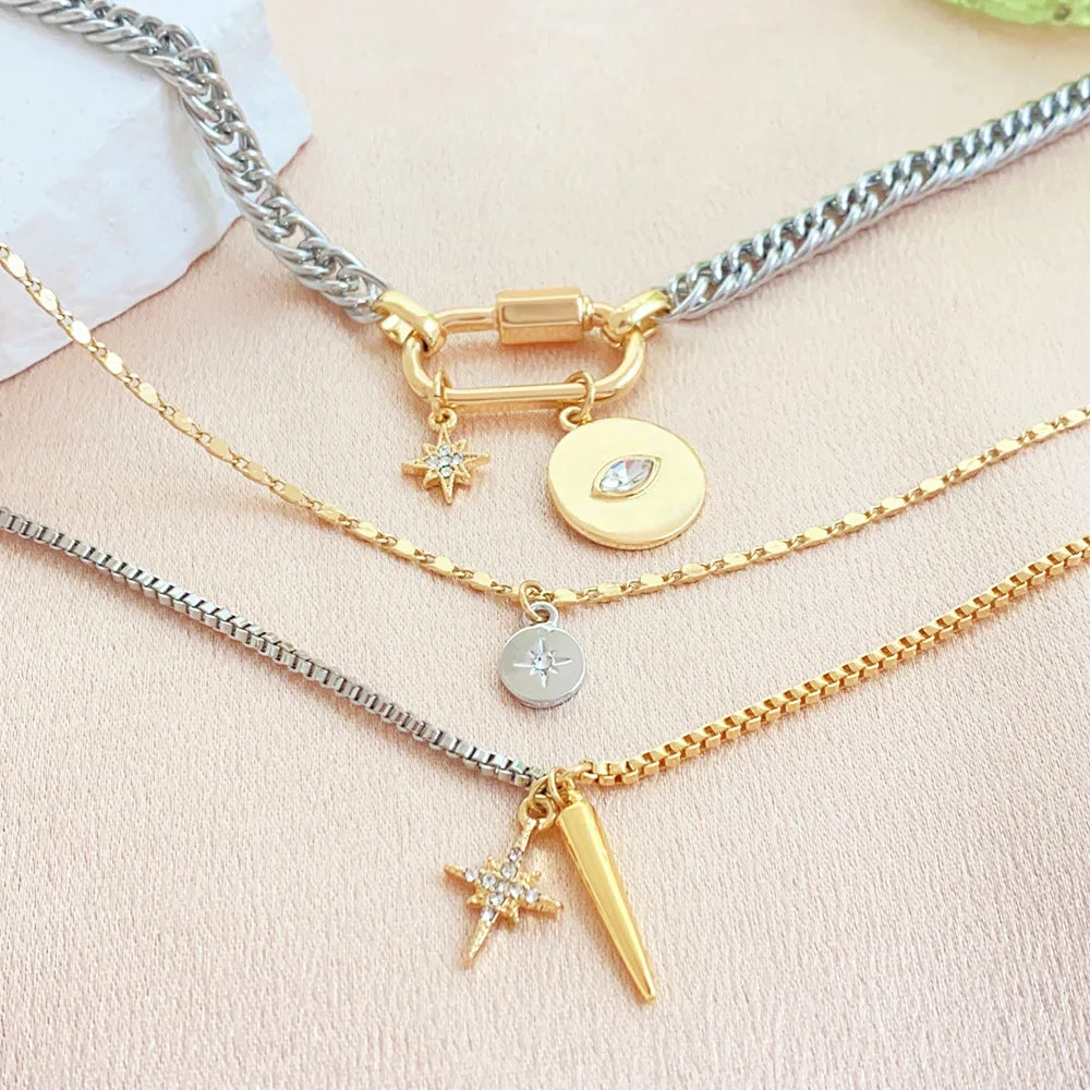 A gold layered necklace featuring a star and eye pendant on a silver chain against a light background.