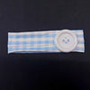 A light blue and white plaid fabric headband with a white button attached.