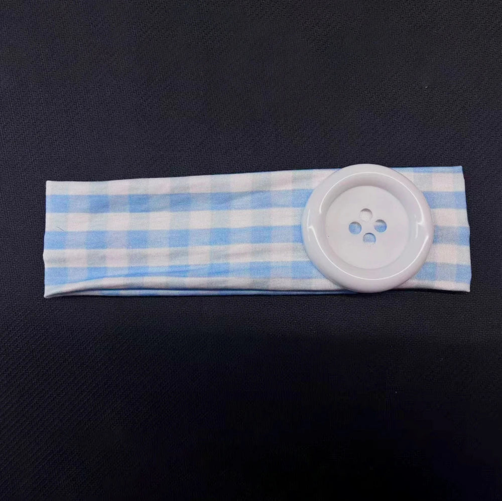 A light blue and white plaid fabric headband with a white button attached.