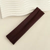 A dark brown fabric headband is shown diagonally against a light background with wavy lines.