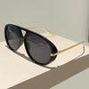 Black aviator style sunglasses with gold accents resting on a light surface.