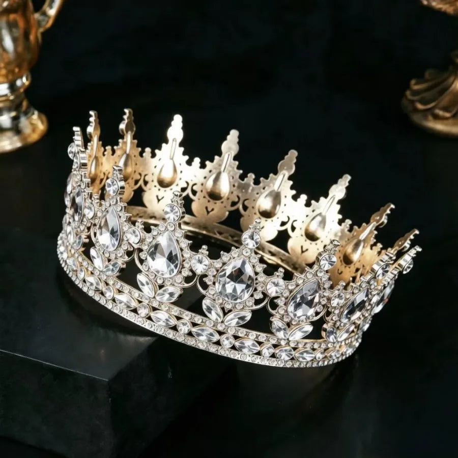 Couronne tiara en strass or et cristal présentée sur une surface sombre.