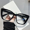 Black retro cat eye sunglasses with clear lenses resting on a white surface.