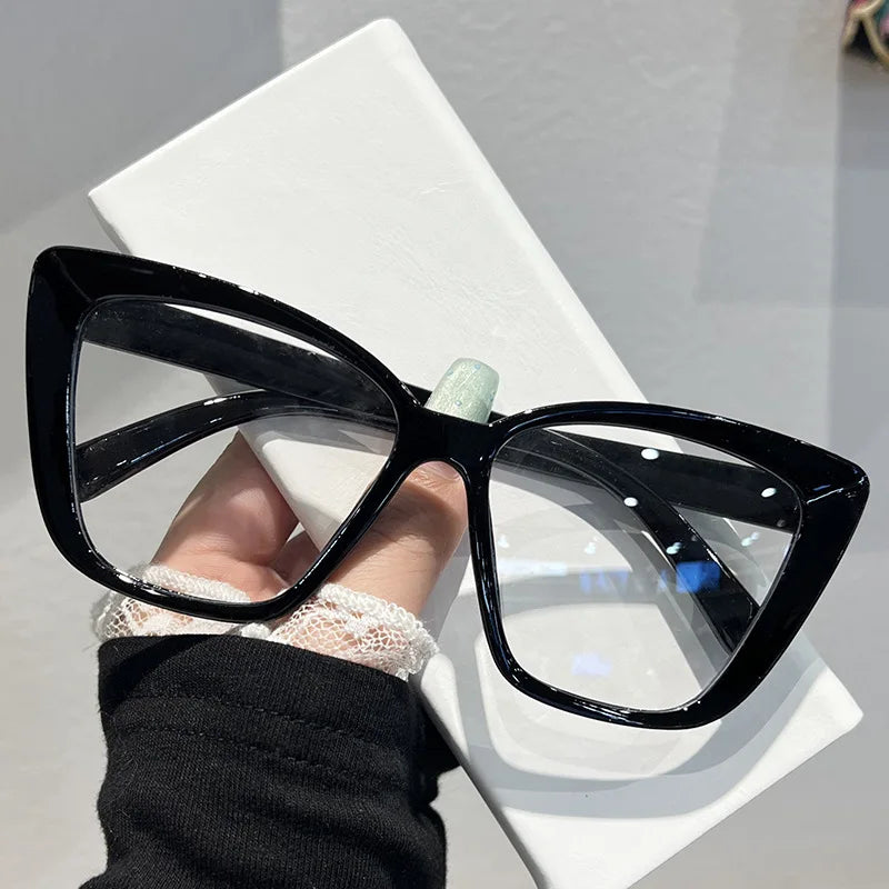 Black retro cat eye sunglasses with clear lenses resting on a white surface.
